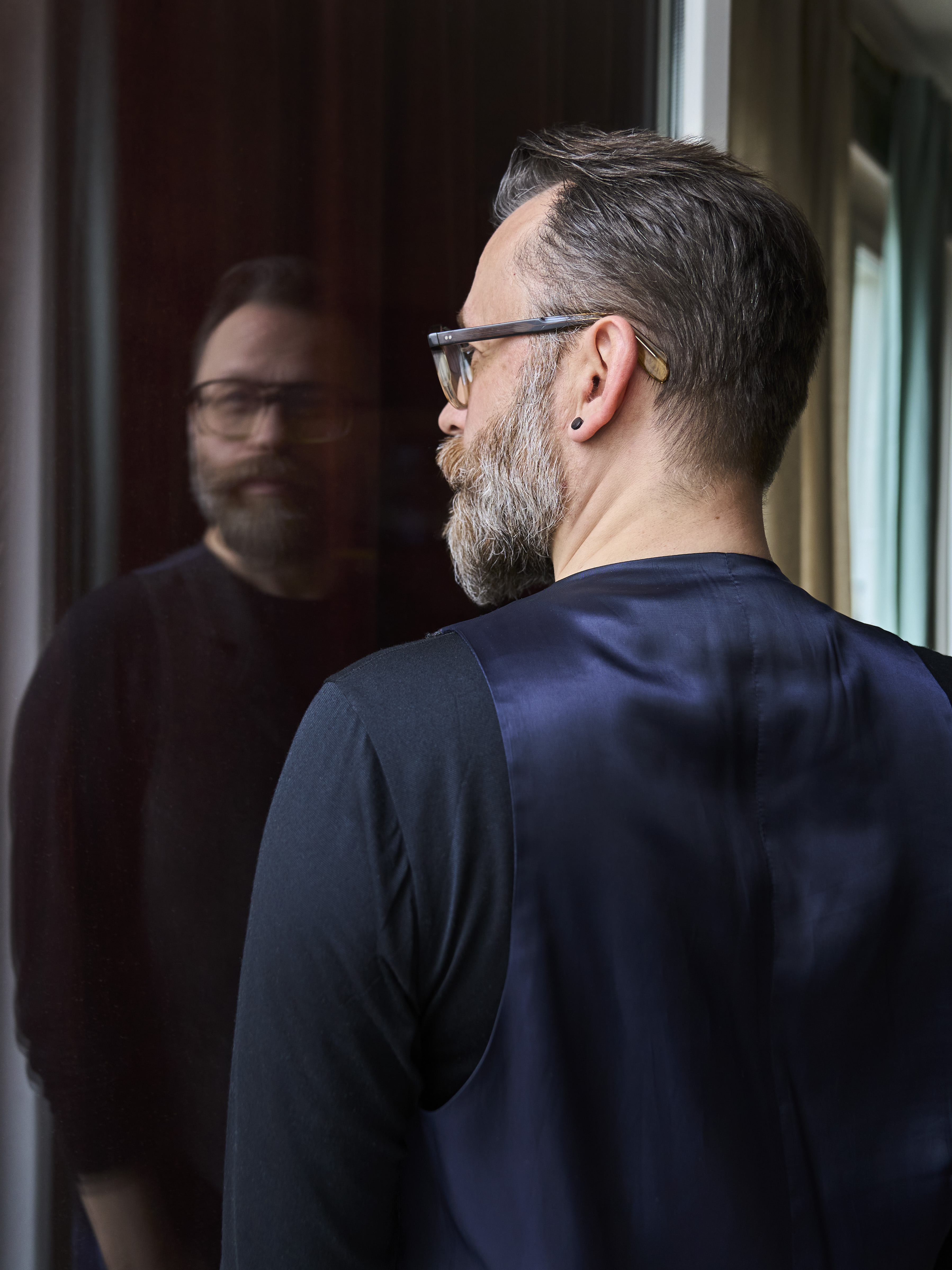 Dominik Grenzler am Fenster, Spiegelung im Glas. Foto: Lea Della Zassa